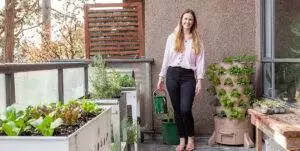 a young blonde woman is planting a vertical tower garden with he