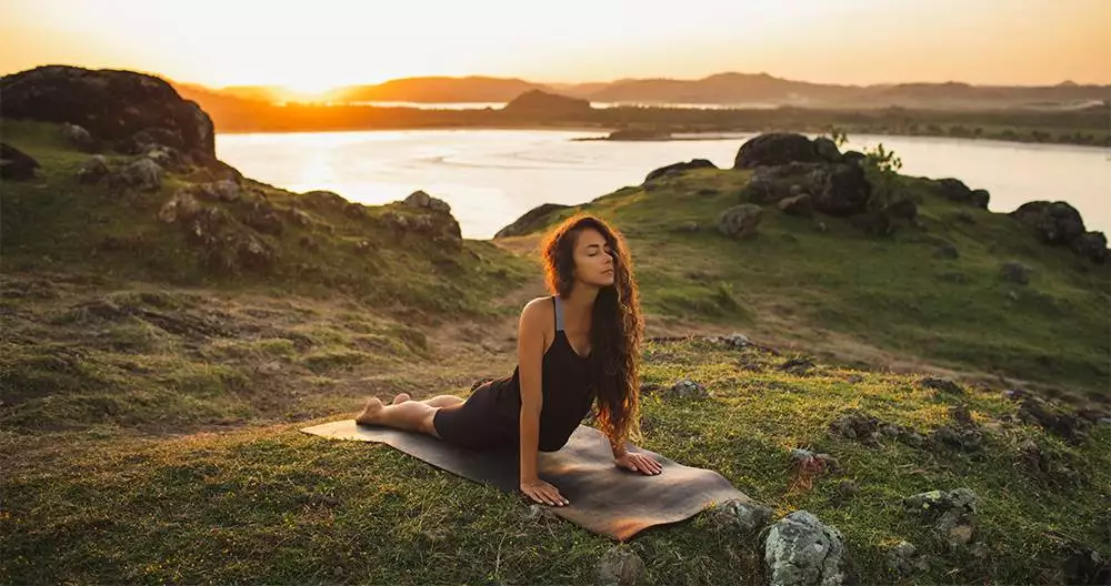 woman training outdoors on yoga mat at sunrise. exercise and stretching