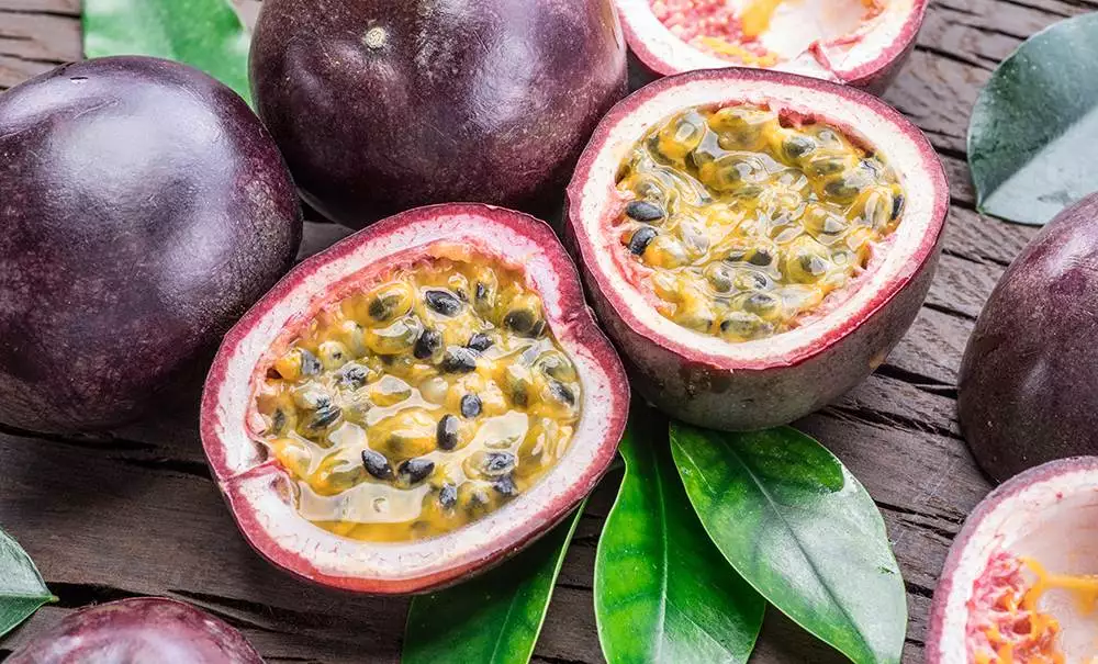 passion fruits and its cross section with pulpy juice filled with seeds. wooden background.